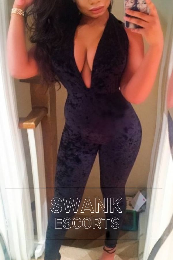 Skye taking a selfie in a black jumpsuit which can barely contain her large boobs