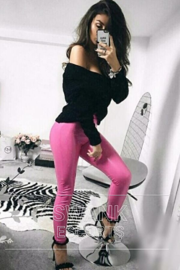 Cara wearing pink jeans, black top and black high heels taking mirror selfie looking sexy 