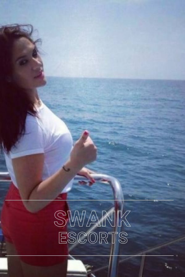 Rebbeca in red shorts and white shirt on a boat giving a thumbs up