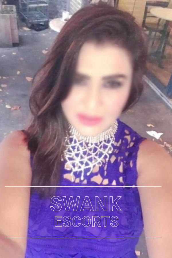 Aesha taking a selfie of her face in a blue dress and silver jewellery