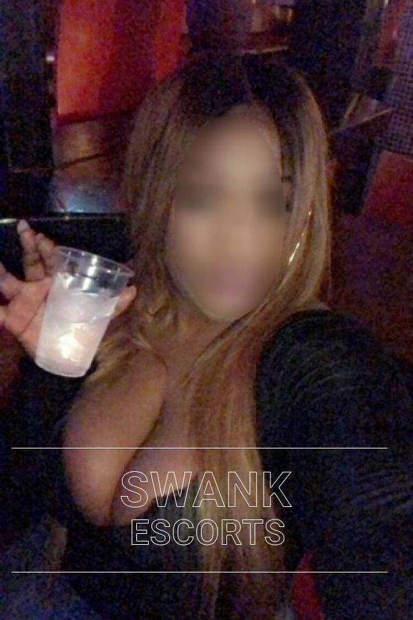 Sian taking a selfie with a drink in hand and her boobs on show in a black top